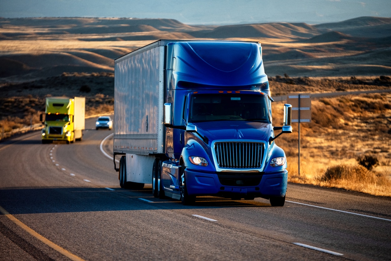 semi-truck driving down an interstate highway at dusk