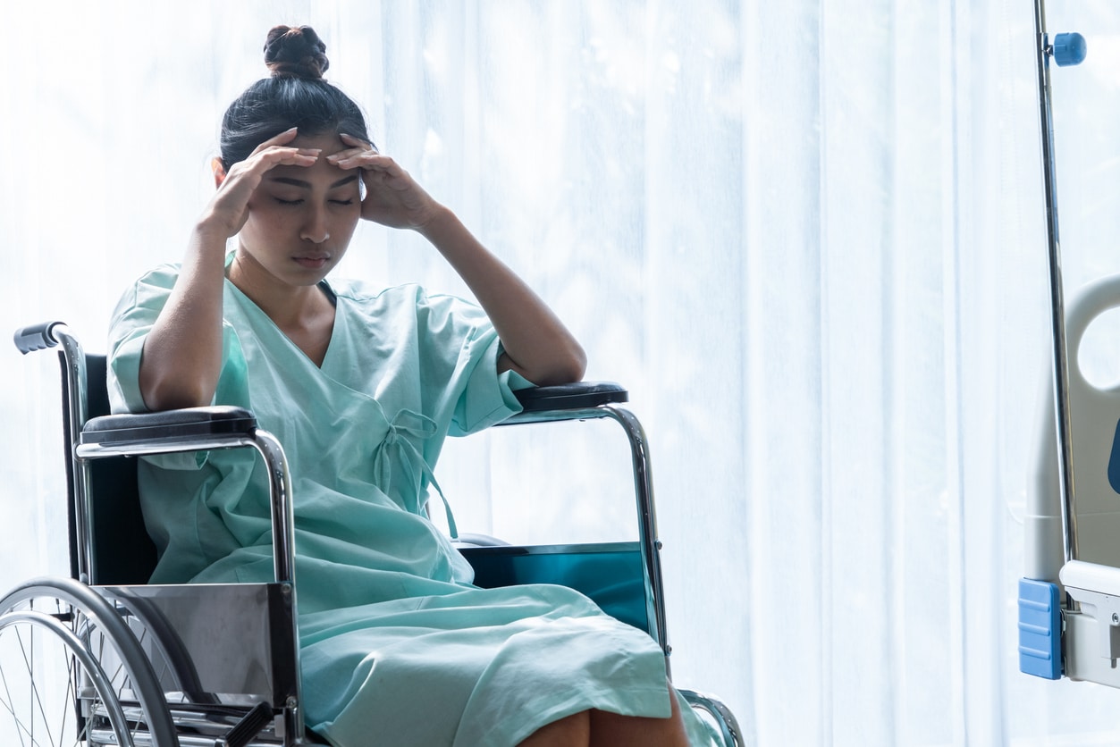 Serious patient sitting on wheelchair in hospital.