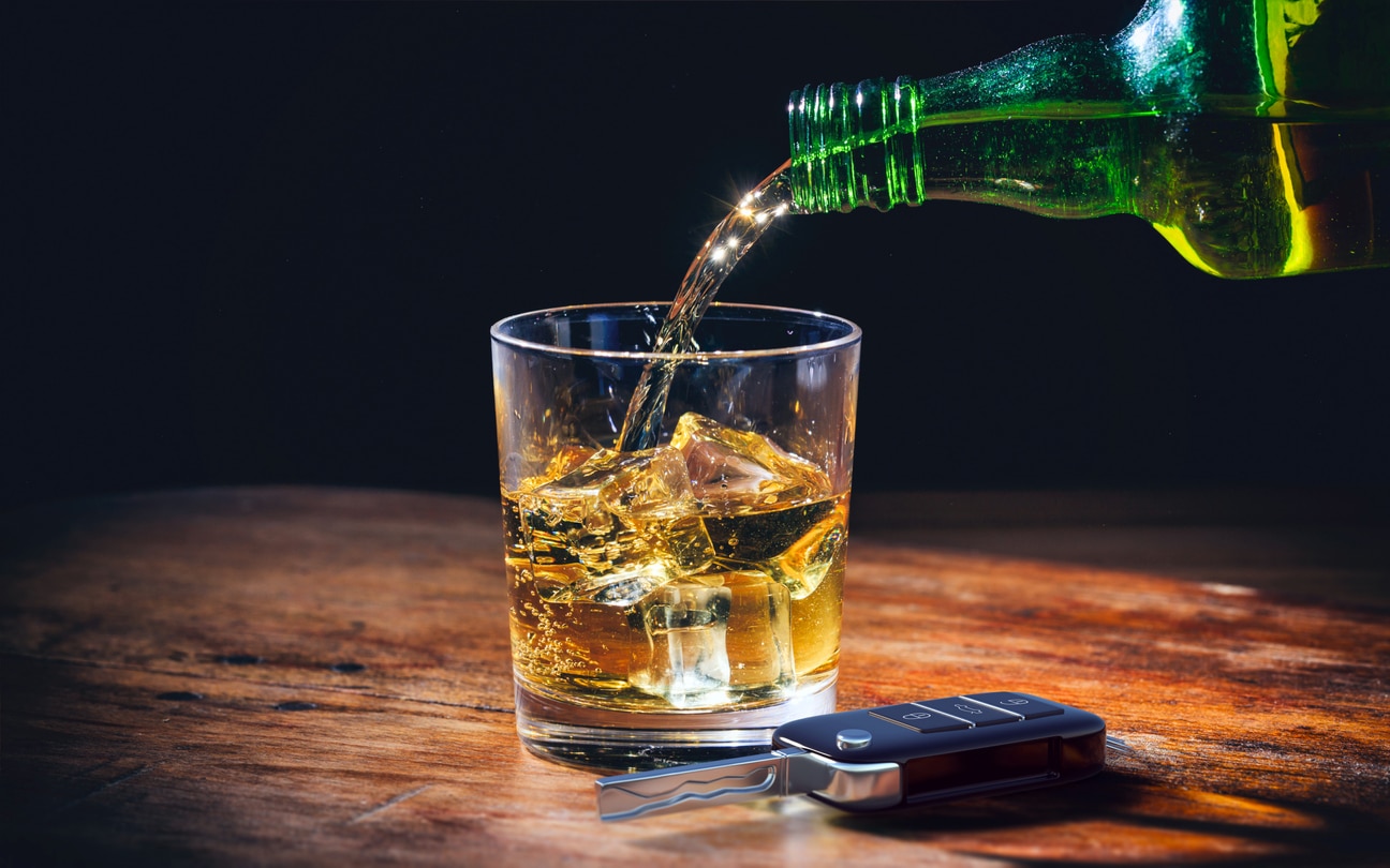Drinking and driving concept. Car key and alcohol glass on wooden background. 3d illustration.