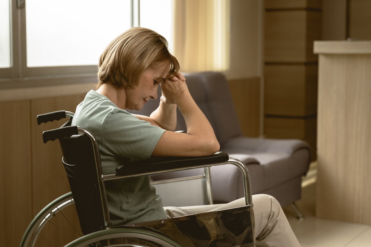 adult women patient feel sad lonely sitting on wheelchair at hospital homecare dim light