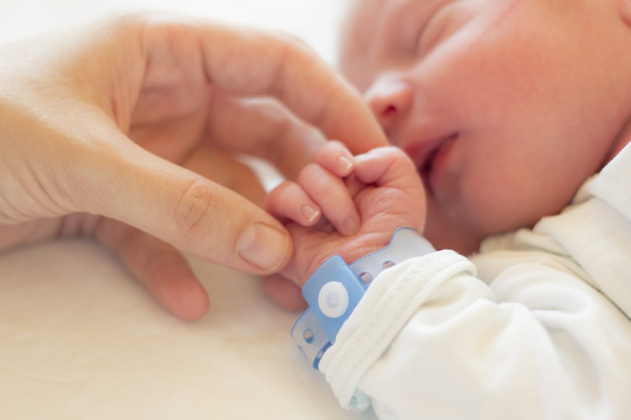 A newborn baby holding a parent's hand