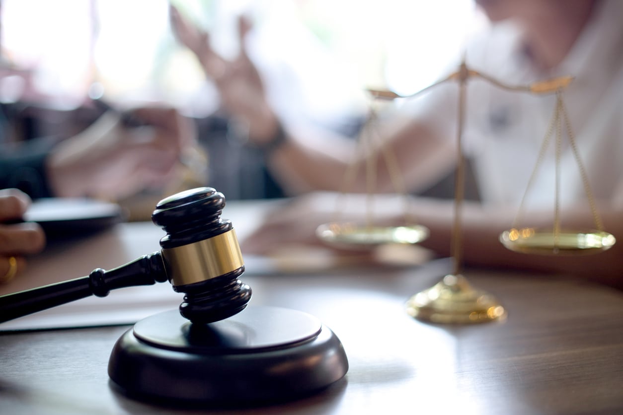 Lawyer Client Talking at Desk With Scales of Justice