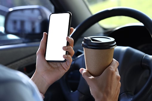 Distracted Driving. Paper cup and smartphone in car, closeup